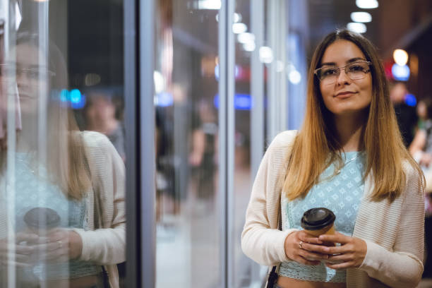 istock Young woman drinking coffee downtown at night 1056502256