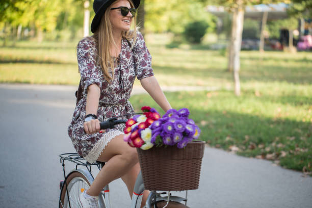 Young beautiful woman riding a bicycle in a park on a sunny day