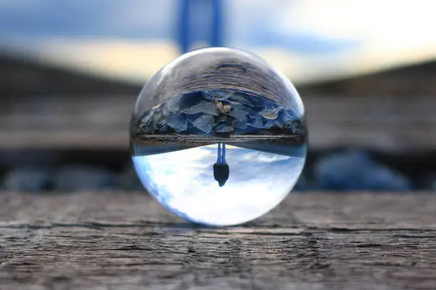 Photo of Refection of a woman walking on the train tracks in a lens ball
