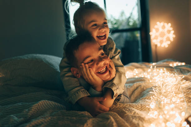 Christmas day in our home Cute boy and a girl lying on the bed in Christmas day christmas excitement stock pictures, royalty-free photos & images