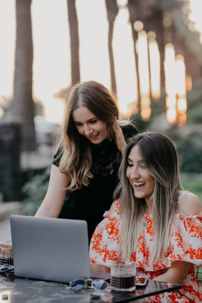 istock Two beautiful females drinking coffee and web surfing 1056523478