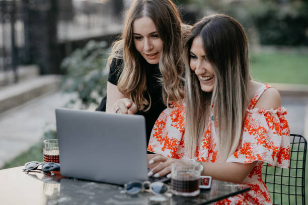 istock Two beautiful females drinking coffee and web surfing 1056528334