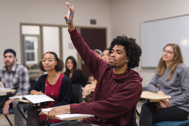 istock Black male college student raising his hand to answer a question during class 1056528352
