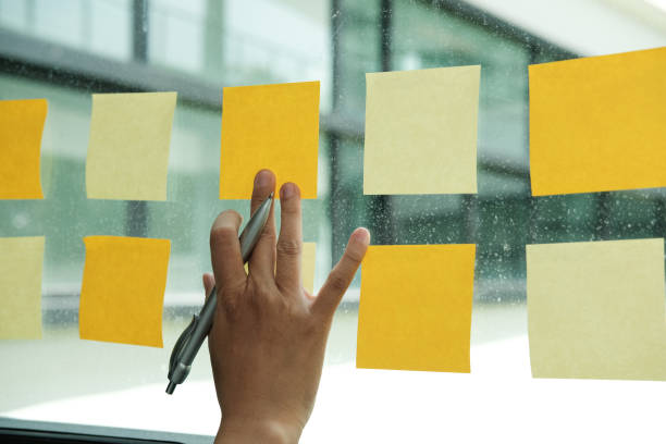 istock hand touch on adhesive notes on glass wall. Sticky note paper reminder schedule for creative idea & business brainstorming 1056532192
