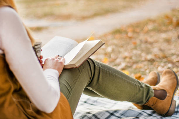 istock Woman reading book in park at retro blanket 1056539354