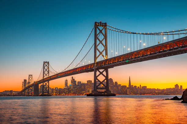 skyline de san francisco con oakland bay bridge en la puesta del sol, california, eeuu - golden gate bridge night bridge san francisco bay fotografías e imágenes de stock