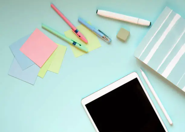Pen, tablet, stickers and Notepad lie on a blue background.
