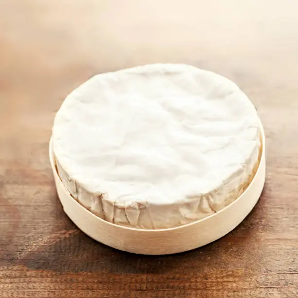Cheese camembert on wooden desk, top view. Soft creamy cheese Brie with copy space"n
