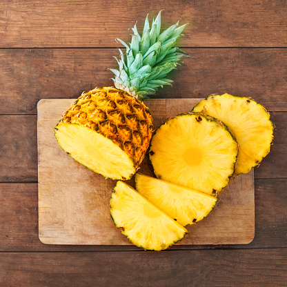 Pineapple on wood texture background. Whole and sliced tropical pineapple on wooden cutting board  with copy space. Top view\