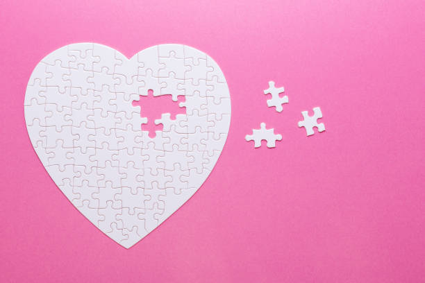 istock White puzzle heart on pink background. Missing piece. Top view 1056608032