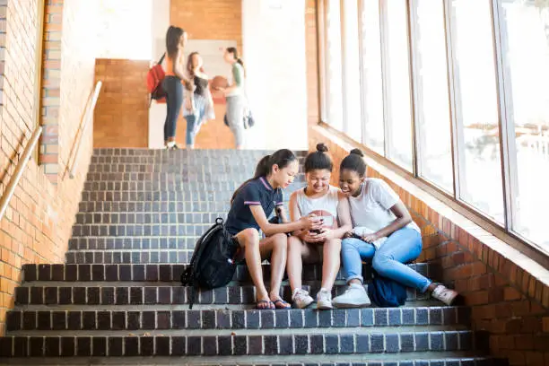 Photo of Friends using mobile phone on steps in high school