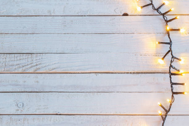 istock Christmas lights on white wooden background 1056619012