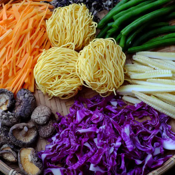 Raw materials for fry noodles mixed vegetables from top view, a Vietnamese vegetarian dish for vegans, with colorful greens, vermicelli and mushrooms, quick to  make for breakfast at home