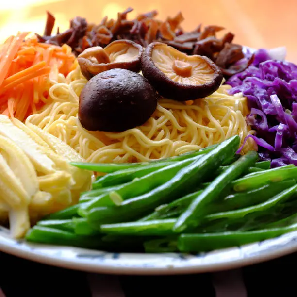 Raw materials for fry noodles mixed vegetables from top view, a Vietnamese vegetarian dish for vegans, with colorful greens, vermicelli and mushrooms, quick to  make for breakfast at home