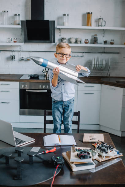 istock adorable boy holding rocket model in kitchen and looking at camera 1056632244