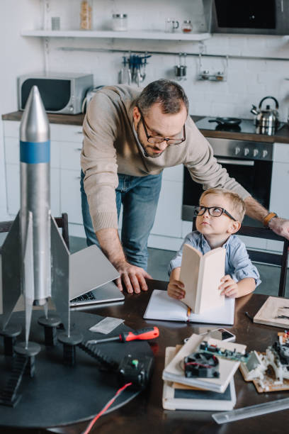 istock father and son modeling rocket and looking at each other at home 1056632282