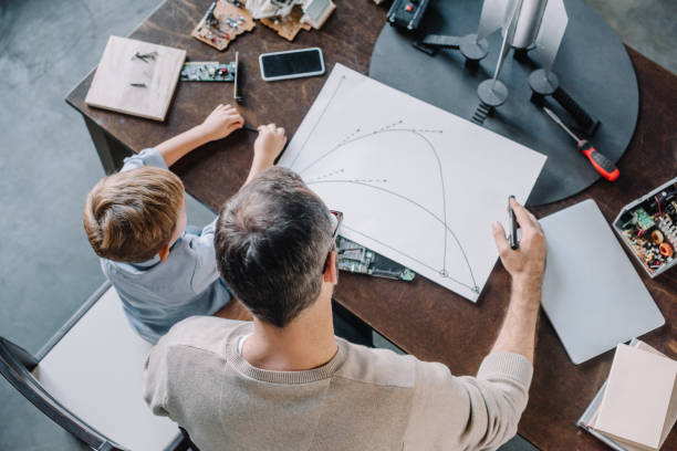 istock overhead view of father and son looking at blueprint for modeling rocket at home 1056632378