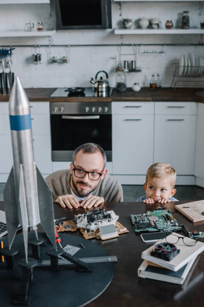 istock father and son looking out from table in kitchen and looking at rocket model 1056632402