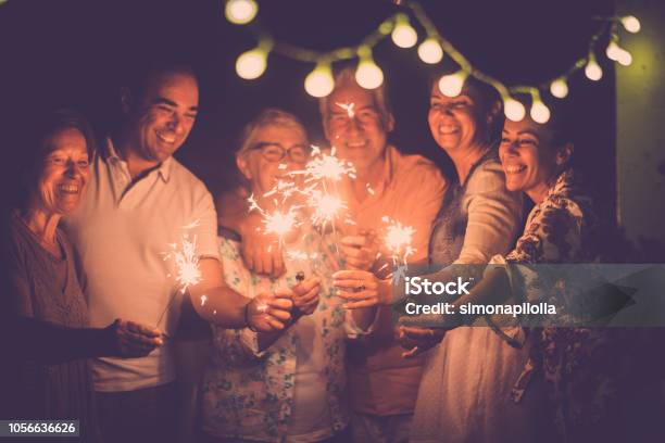 Group Of Caucasian People Friends With Different Ages Celebrate Together A Birthday Or New Year Eve By Night Outdoor At Home Lights And Sparkles With Cheerful Women And Men Having Fun In Friendship Stock Photo - Download Image Now