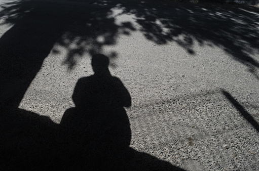 the shadow of a man holding a camera, self-portrait of a tourist photographer, gray street floor.