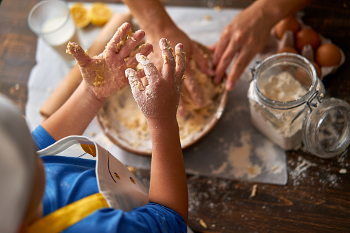 6-7 years old child and his mother are making a cake at kitchen together