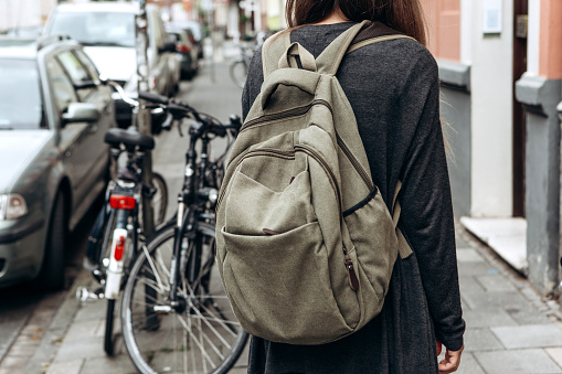 Tourist with a backpack is looking for booked online accommodation in an unfamiliar city. Or a student girl with a backpack is walking through the city.