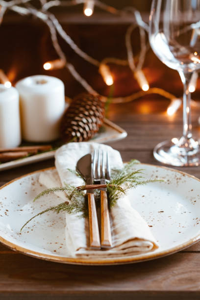 istock Decorated Thanksgiving or New Year table setting among white candles and winter decor. The concept of a festive dinner. 1056642018