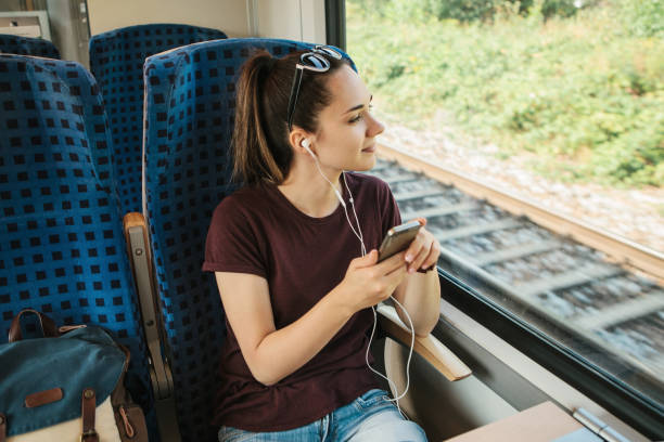 una joven escucha una música o un podcast mientras viaja en un tren - city of nice audio fotografías e imágenes de stock