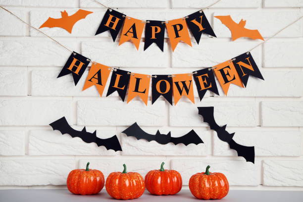 istock Orange halloween pumpkins with paper bats on brick wall background 1056646488