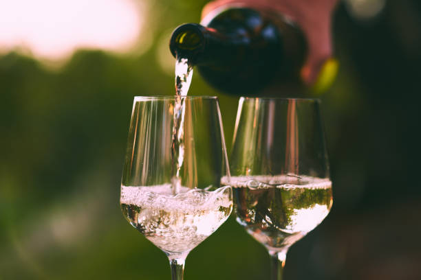 istock Pouring white wine into glasses 1056649760