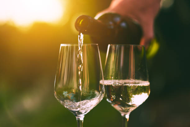 istock Pouring white wine into glasses 1056649928