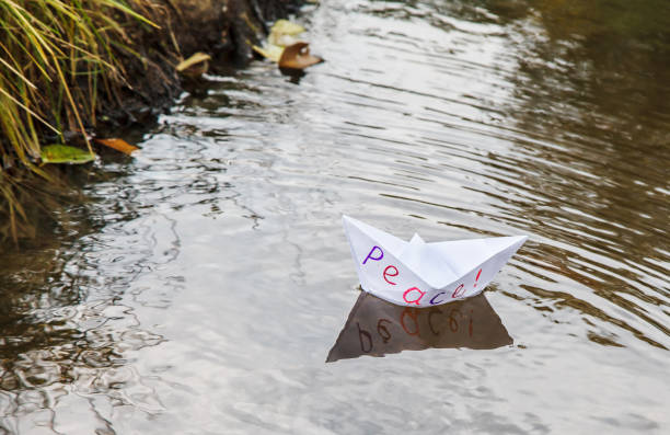 istock lonely white paper boat called peace floating on a stream 1056651504