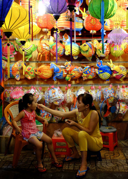 HO CHI MINH CITY, VIET NAM- SEPT 8, 2018: Mother and daughter sit front of colorful lanterns kiosk at lantern street, district 5, Saigon, Vietnam