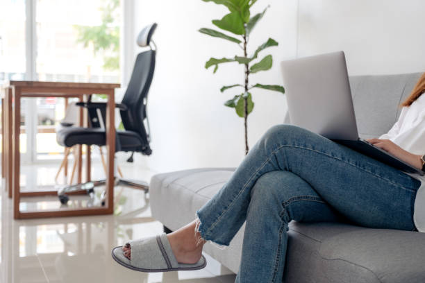 istock Closeup image of woman using and typing on laptop keyboard while sitting on sofa with feeling relaxed 1056655378