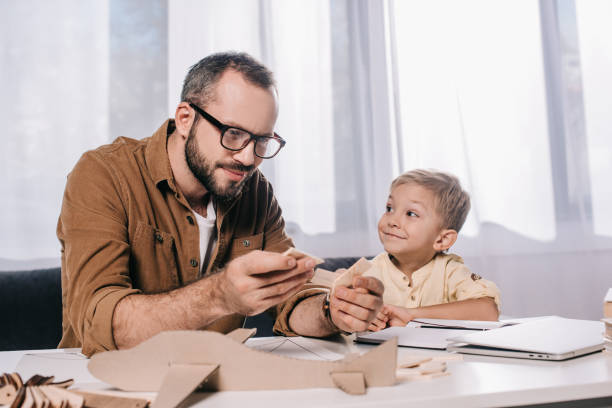 istock adorable happy son looking at smiling father modeling toy plane at home 1056656128