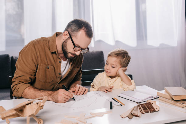 istock focused father and son modeling wooden plane at home 1056656200
