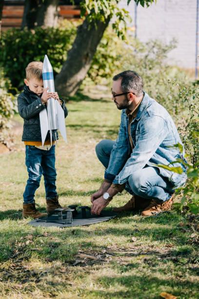 istock father and son playing with model rocket together at sunny day 1056656352