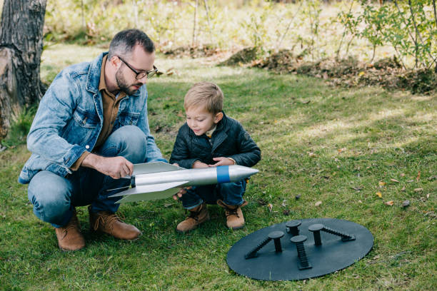 istock father and little son playing with model rocket on grass 1056656364