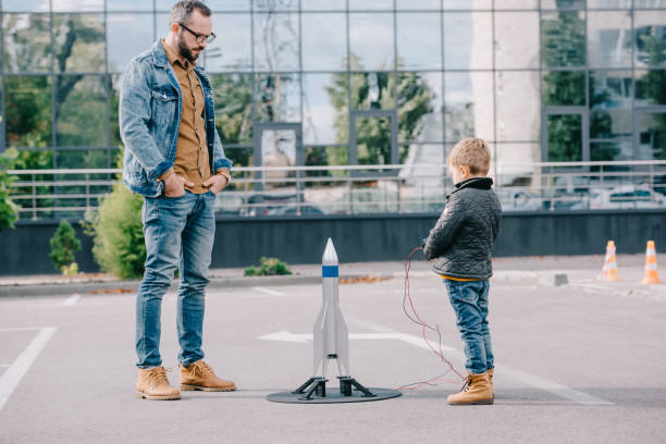 istock father looking at little son launching model rocket outdoor 1056656376