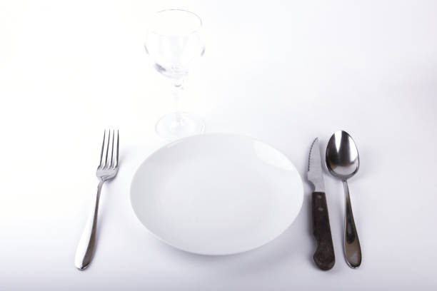 istock Empty white plate, fork, knife, spoon and empty wine glass, isolated on white background 1056657308