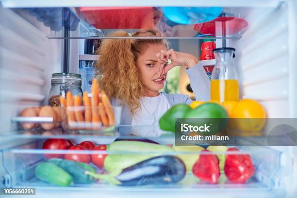 Woman Standing In Front Of Opened Fridge And Holding Up To Her Nose Stock Photo - Download Image Now