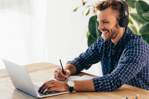istock smiling man in headphones taking part in webinar at tabletop with notebook in office 1056663384