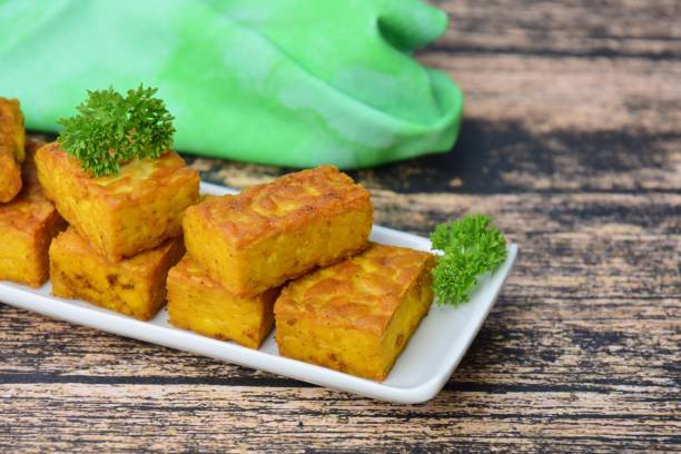 istock Fried cube tempeh with parsley on wooden background 1056664652