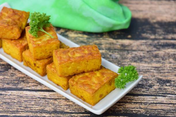 istock Fried cube tempeh with parsley on wooden background 1056664706