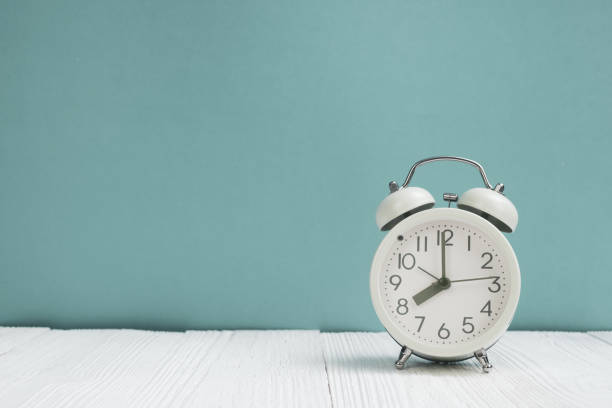 istock Retro alarm clock on white wood table front green wall background, time concept 1056667894