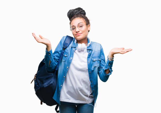 young braided hair african american student girl wearing backpack over isolated background clueless and confused expression with arms and hands raised. doubt concept. - head and shoulders audio imagens e fotografias de stock