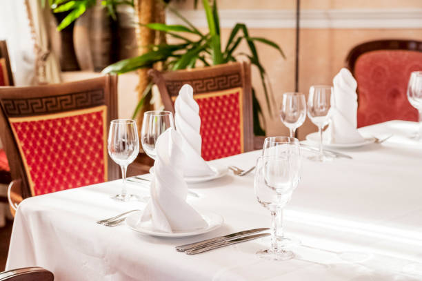 istock Table setting in a restaurant, cafe in the style of the Soviet Union. White tablecloth, glasses, plates, appliances, red furniture 1056669664
