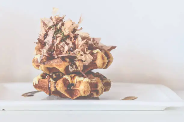 Belgian Liege waffles topped with flamed takoyaki sauce, Japanese mayonnaise, Japanese spices and bonito flakes