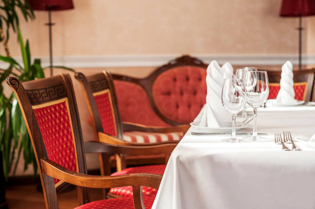 istock Table setting in a restaurant, cafe in the style of the Soviet Union. White tablecloth, glasses, plates, appliances, red furniture 1056669686