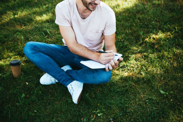 istock cropped image of smiling man making notes on green grass in park 1056669904